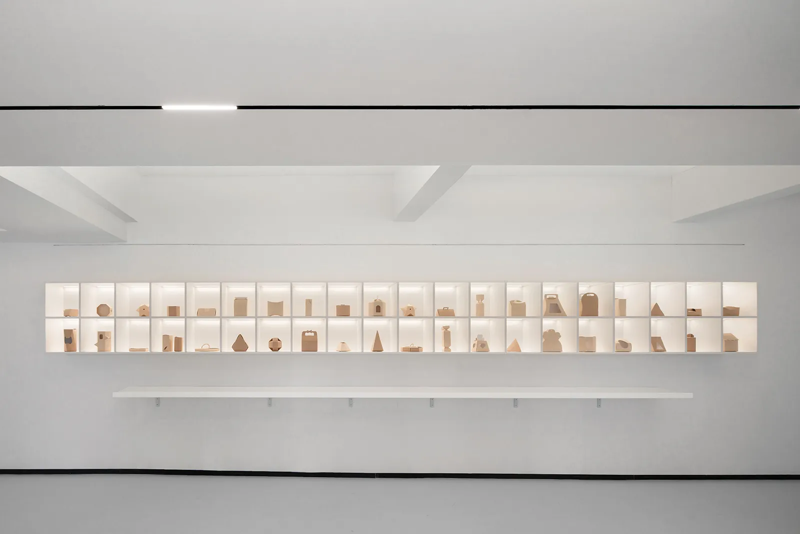 極簡藝術展覽，展示各種紙雕作品陳列於發光展示架上。