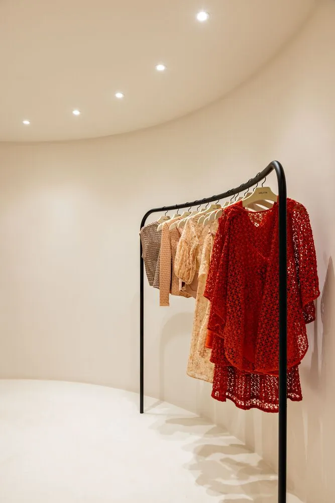 A clothing rack displaying various garments on metal hangers in a fashion store setting.