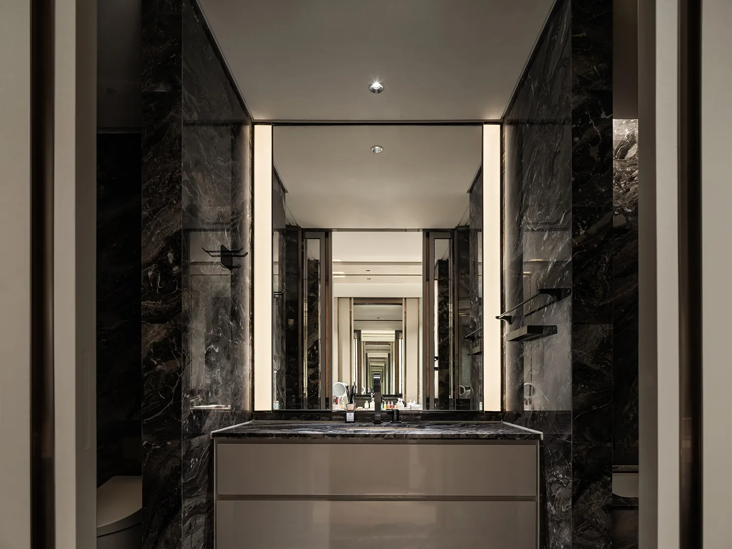 Modern bathroom with marble walls and floor, featuring a sleek vanity and mirror.
