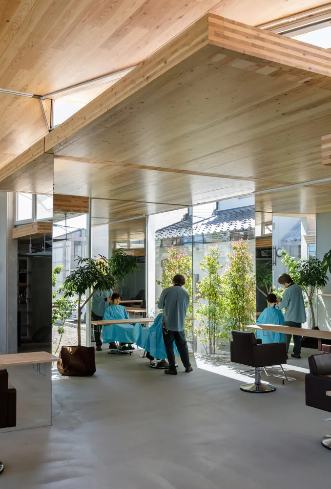Modern salon interior designed with wooden panels and concrete floors, featuring clients and stylists in action.