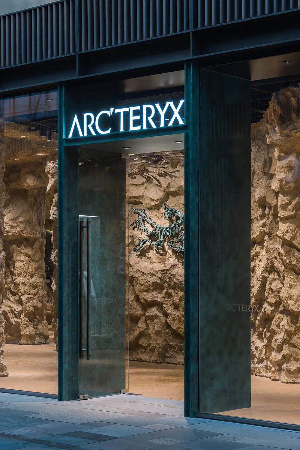 現代店面入口採用玻璃材質，石材牆面搭配 Arc'teryx 發光標誌。