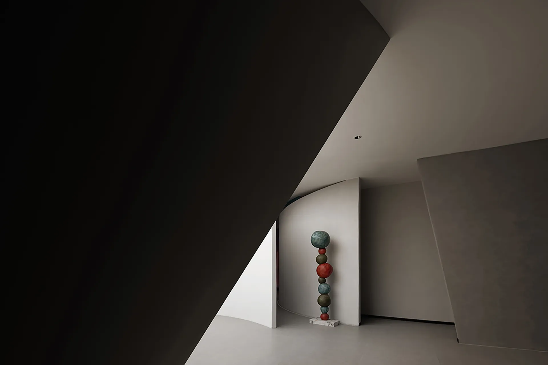 A modern interior space featuring a sculpture made of stacked, multicolored spheres on a pedestal.