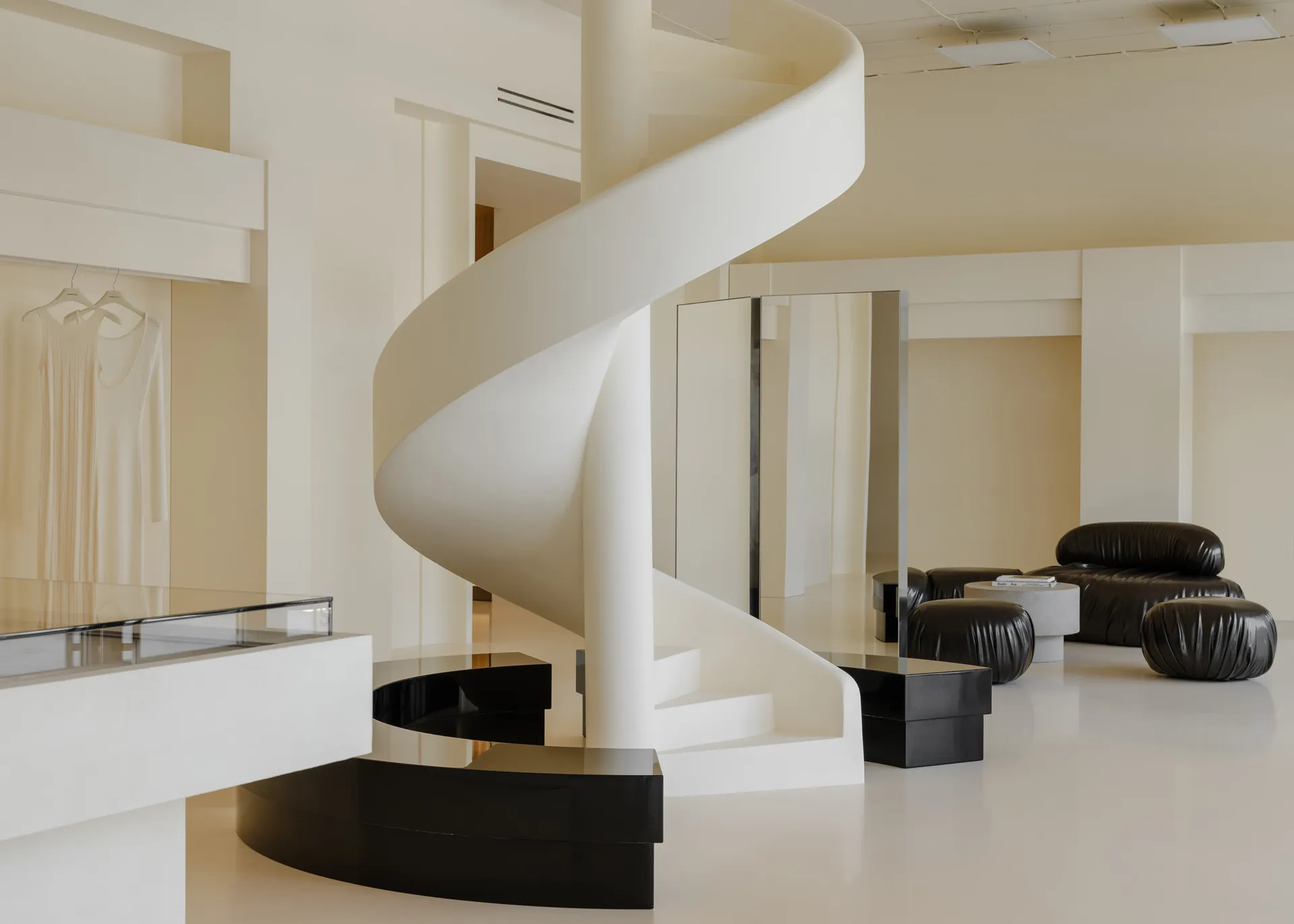 Modern store interior with white stone walls, black metal accents, and black leather seating.
