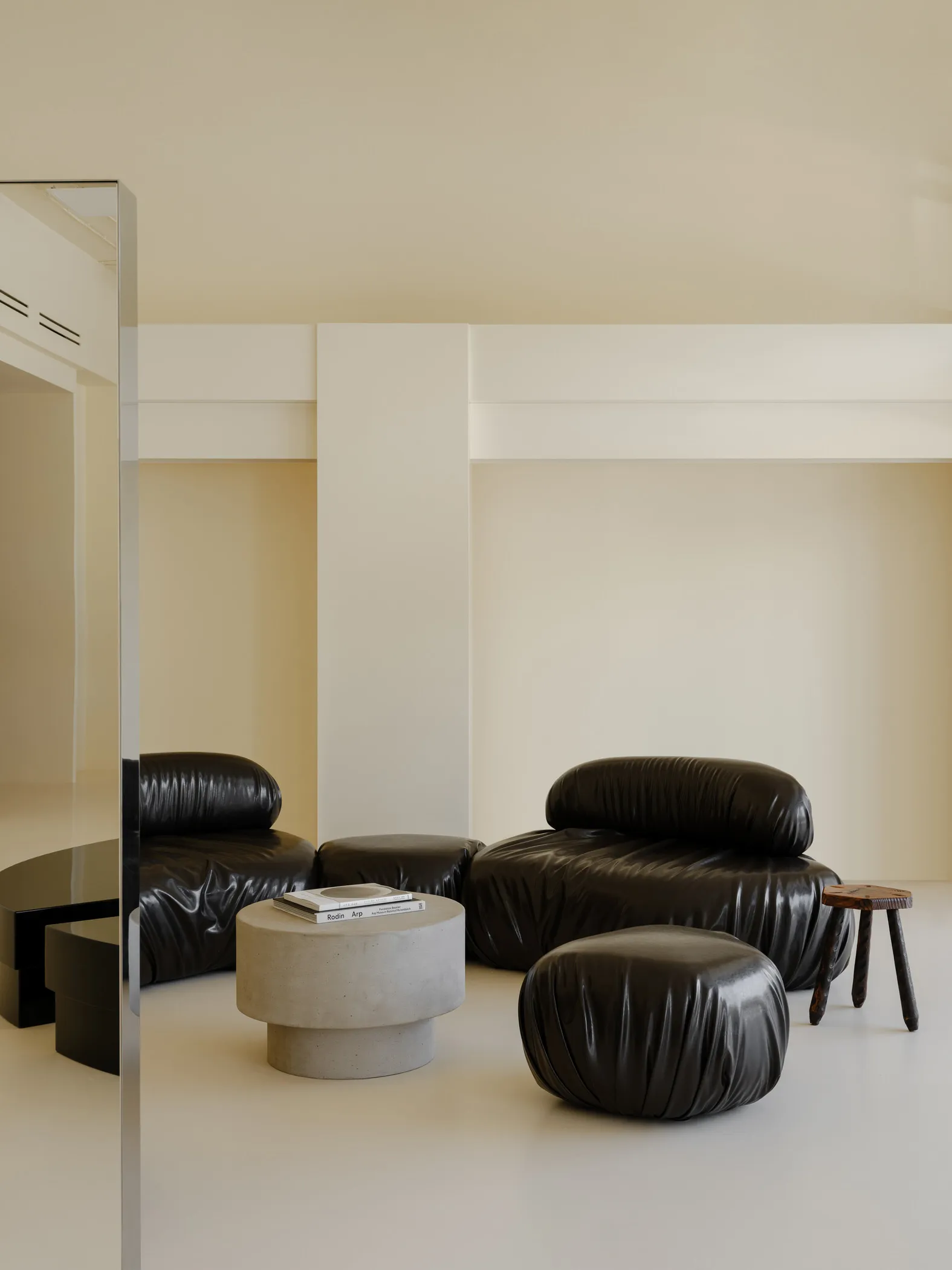 A modern living space with a black leather armchair, round concrete coffee table, and minimalist decor.
