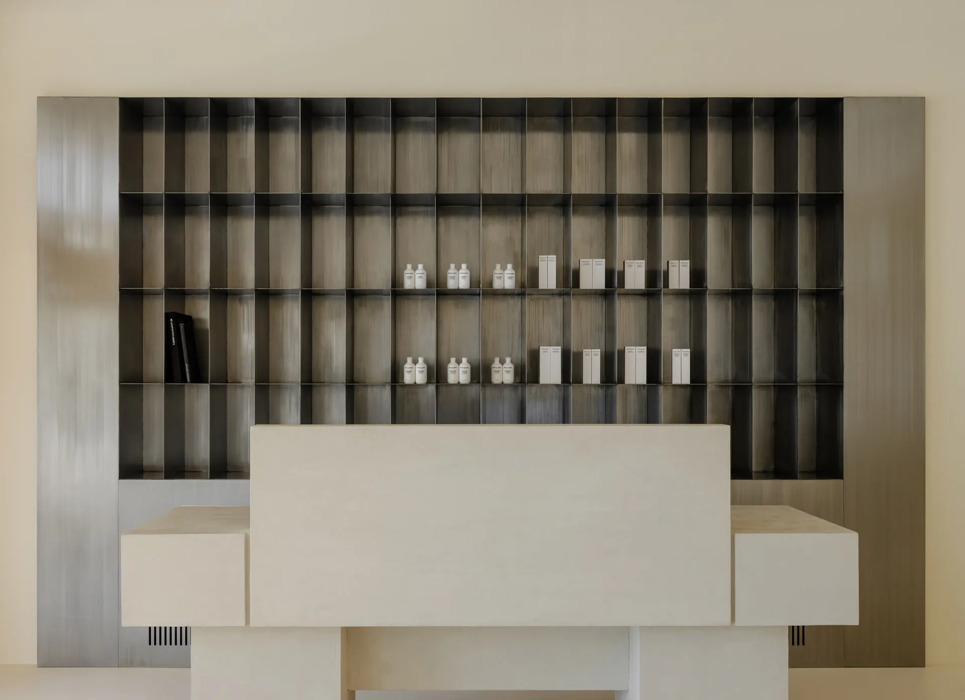 A minimalist modern interior with a metal shelving unit displayed against a beige wall.
