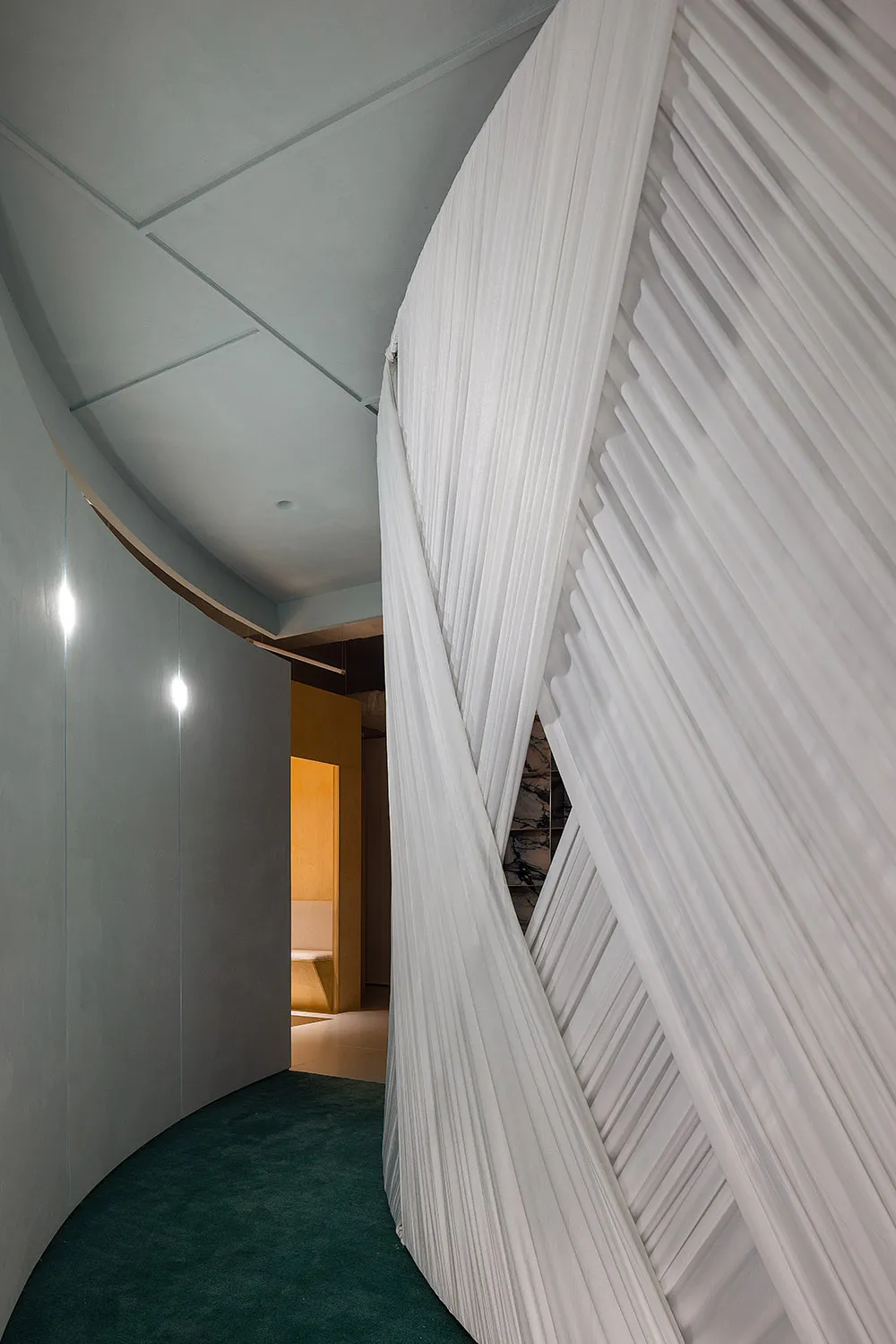 A minimalist interior with modern, white curtains and metallic accents.