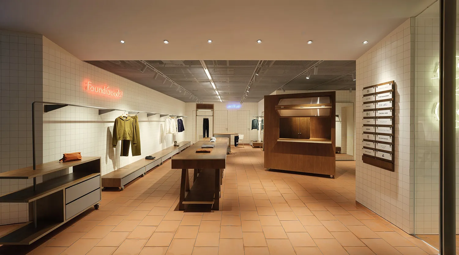 零售服裝店內部，展示瓷磚地板與木製陳列桌。
