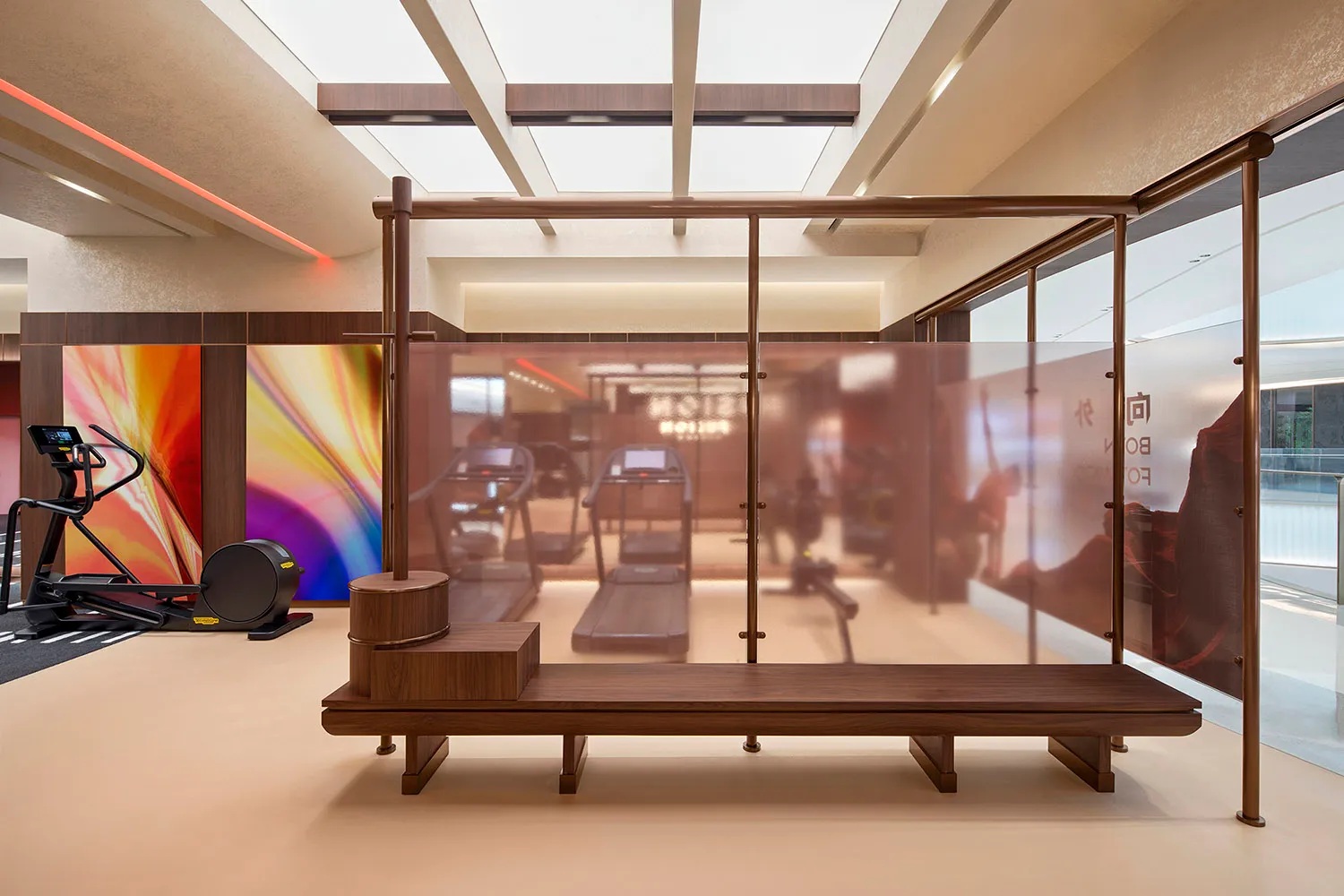 Minimalist gym interior with wooden benches and glass dividers, featuring modern fitness equipment.