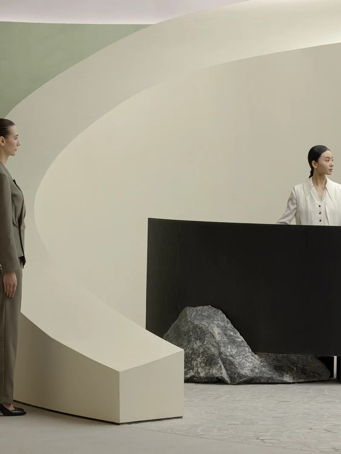 A minimalist interior design featuring a concrete structure and a woman in a white dress.