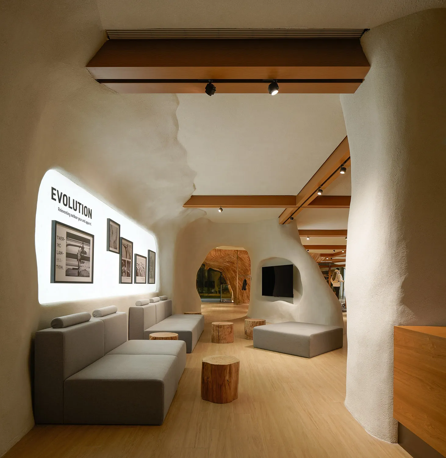 A modern lounge with concrete and wooden elements featuring a curved wall, comfortable seating, and a flat-screen television.