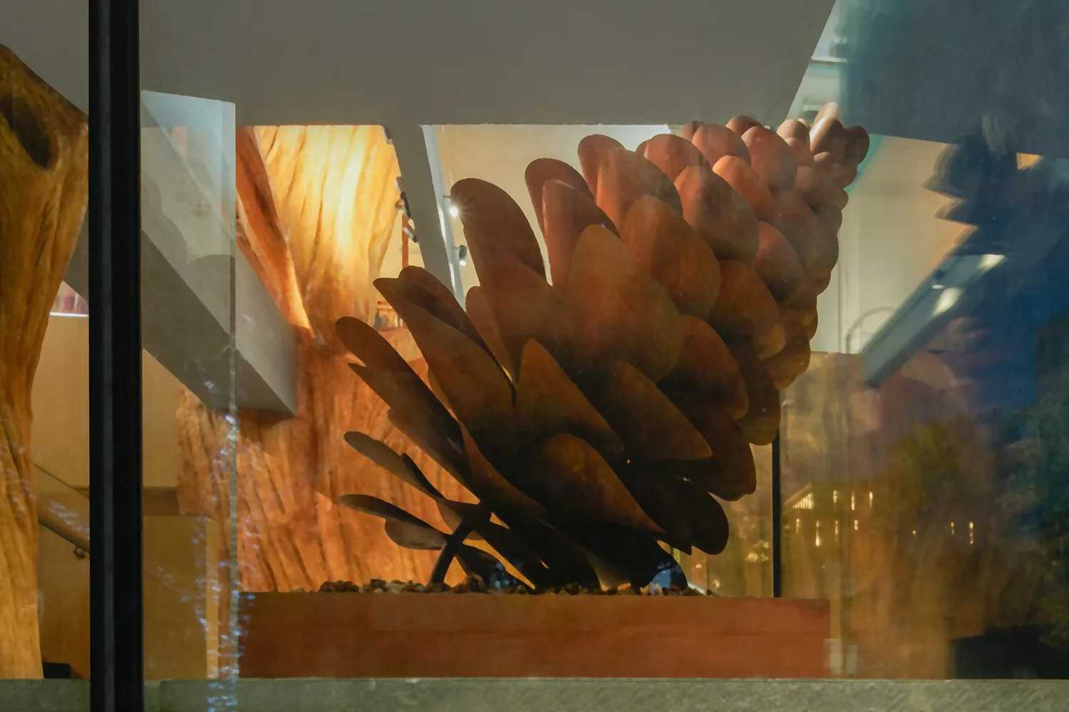 A modern metal sculpture displayed on a wooden platform, featuring intricate designs and an industrial aesthetic.