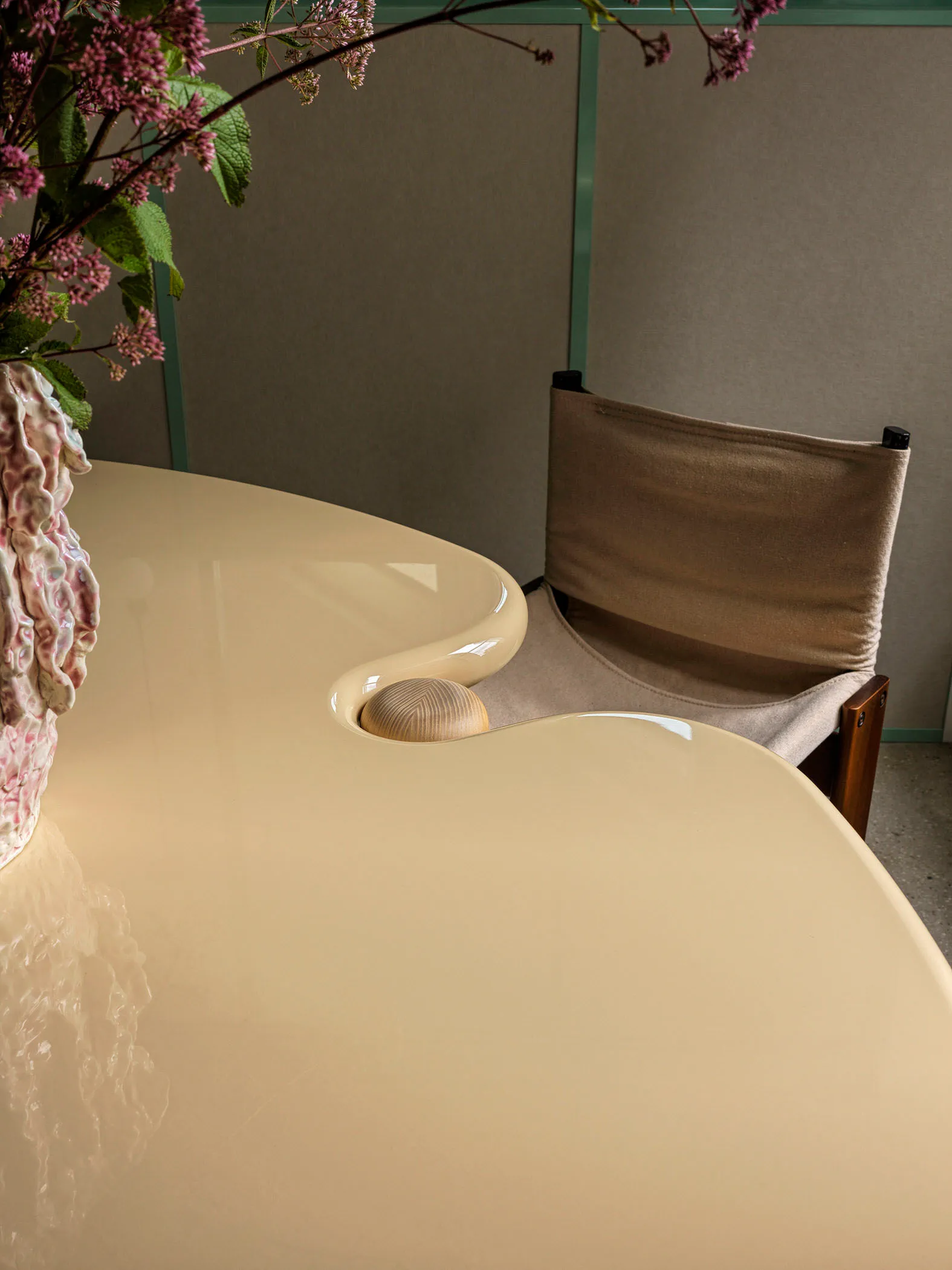 Modern dining room with ceramic table, floral arrangement, and wooden chair.
