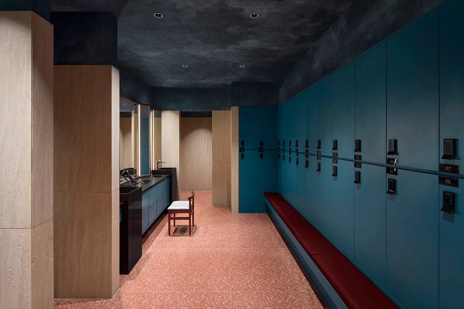 Modern locker room with terrazzo flooring, wooden benches, and metal lockers with numbered keys.