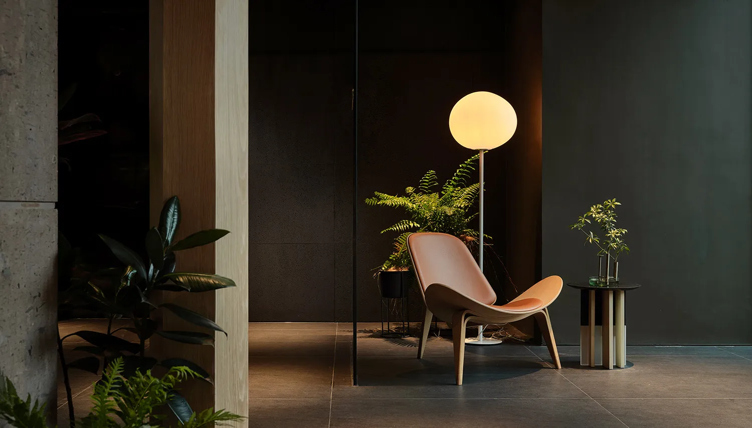 Modern interior design featuring a wooden chair, floor lamp, and plants in a living space.