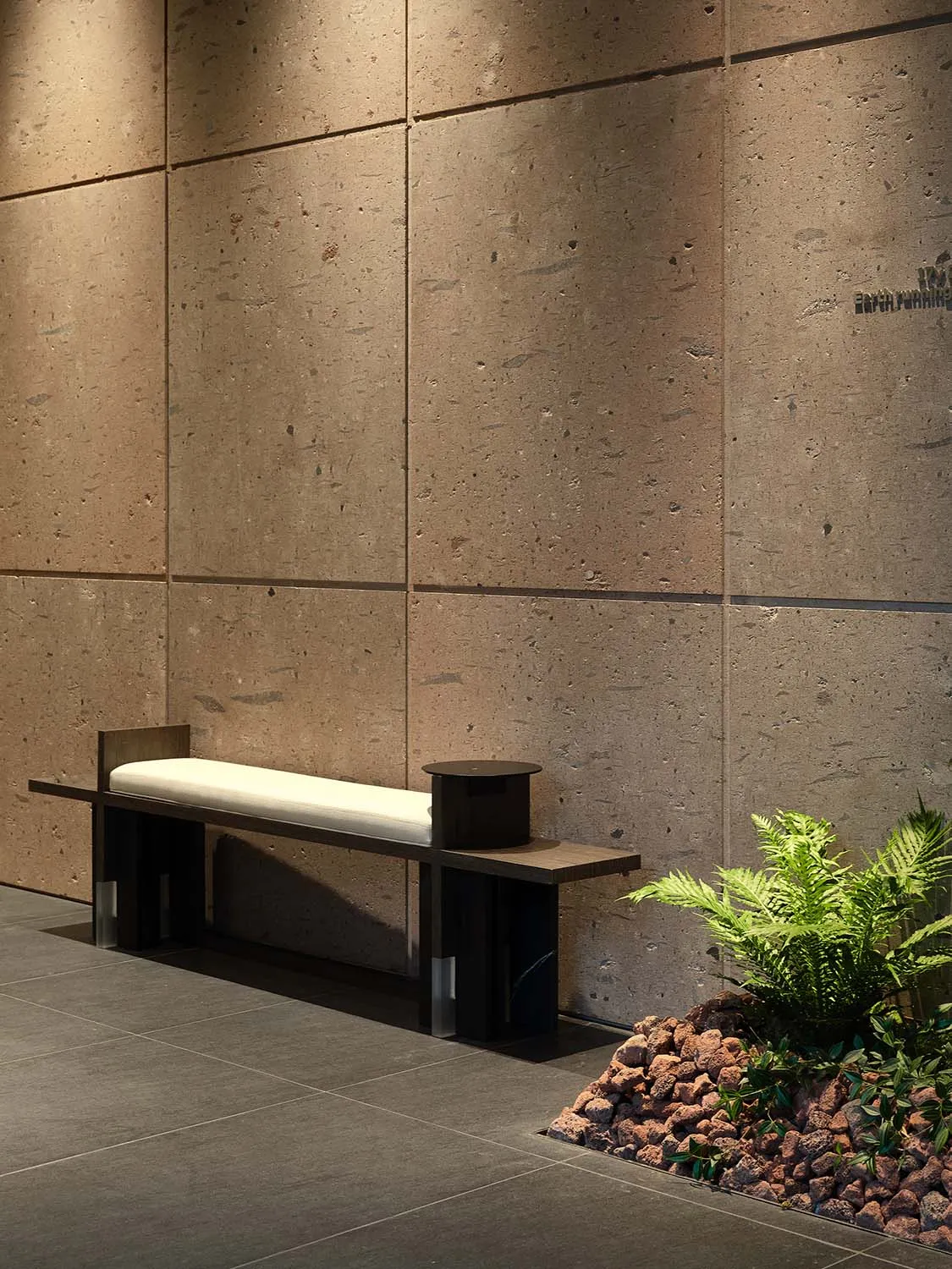 A contemporary lobby with a minimalist design featuring a concrete wall and a simple white bench.