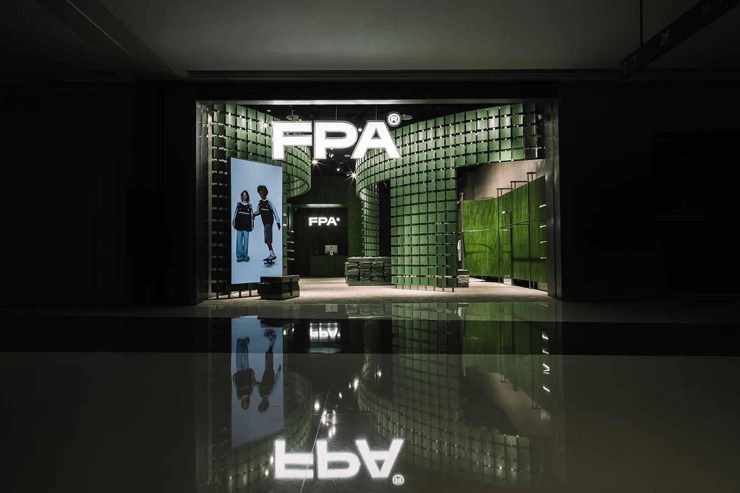 A minimalist storefront with a metal facade and green tiles.