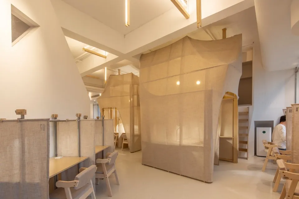 A workspace with fabric-walled partitions and wooden furniture.