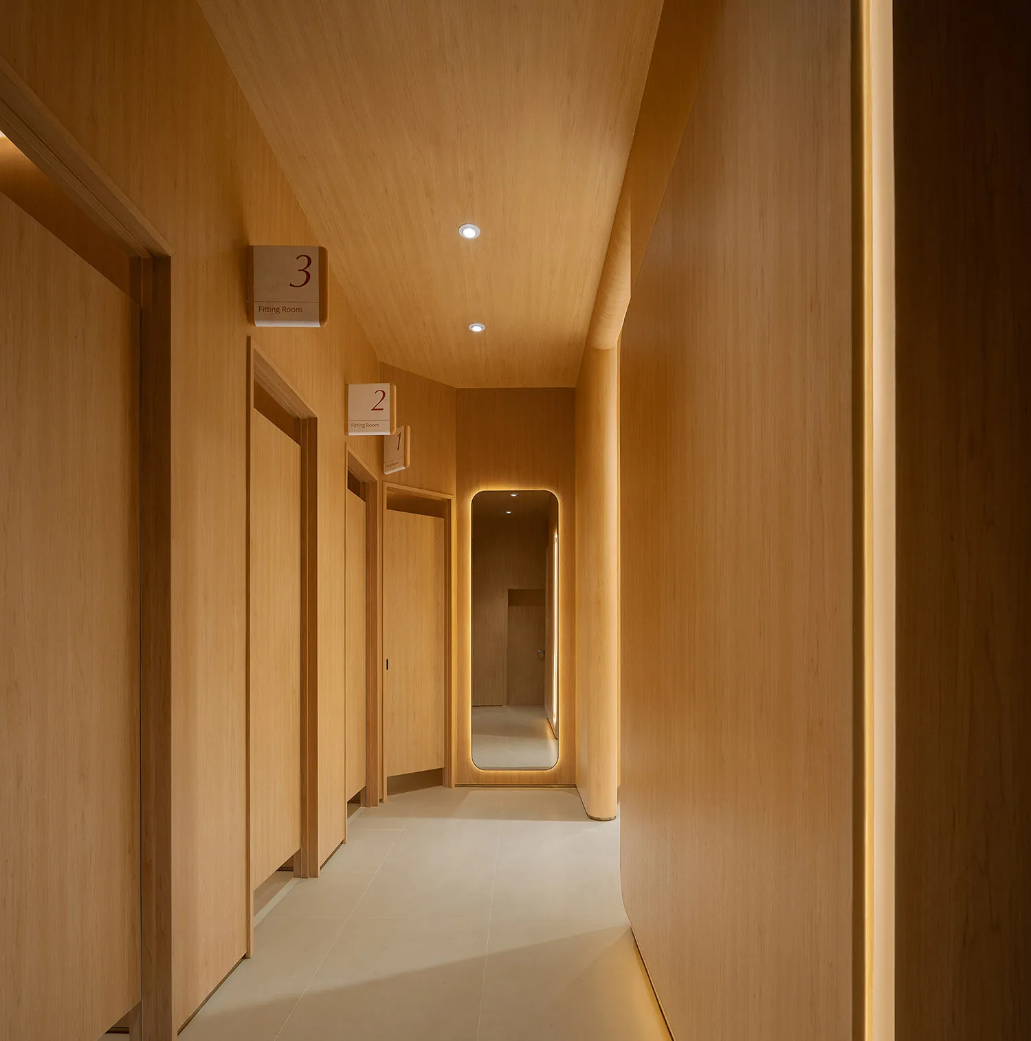 Minimalist wooden corridor with numbered fitting rooms.