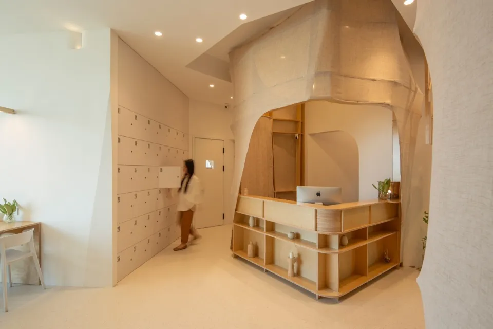 A minimalist reception desk with wooden shelves and a sleek design, featuring a laptop on the counter.