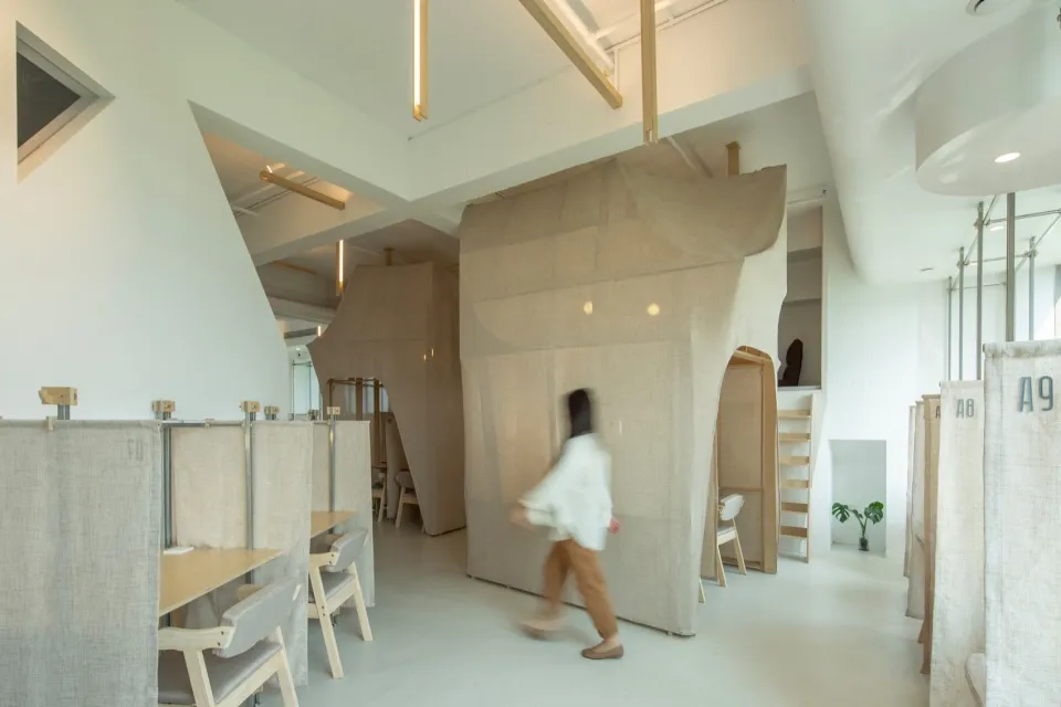 A minimalist workspace with fabric dividers and a concrete floor.