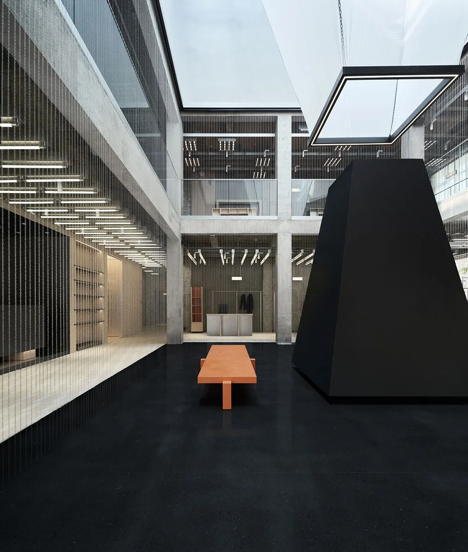 An interior office lobby with minimalist design, featuring concrete, glass, and metal materials.