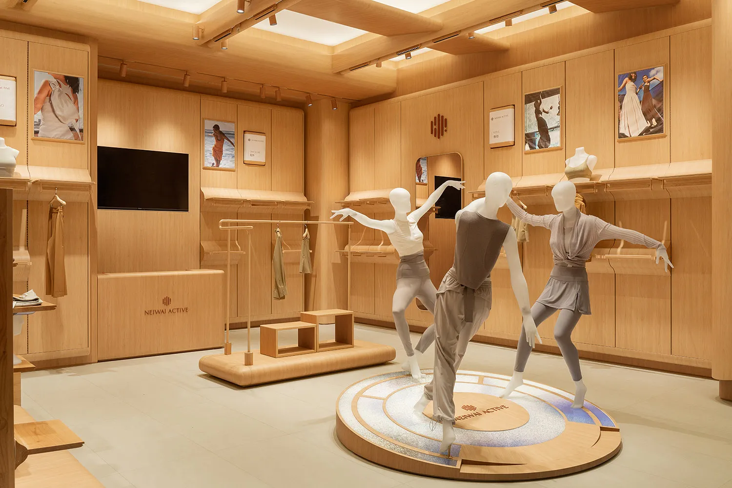 A modern retail space with mannequins displayed on a circular platform, surrounded by wooden walls and shelves.
