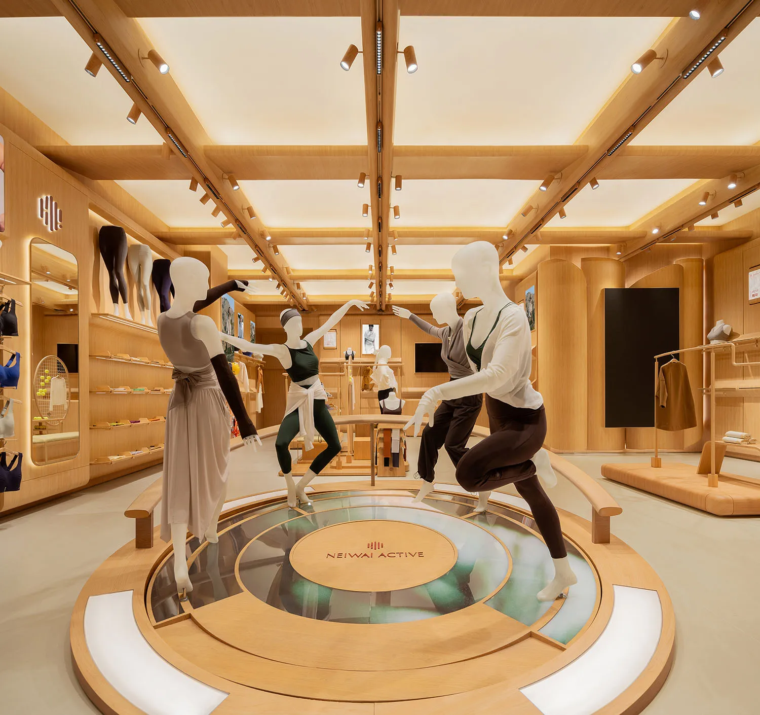 Modern retail store interior with wooden platform displaying mannequins dressed in athletic wear.