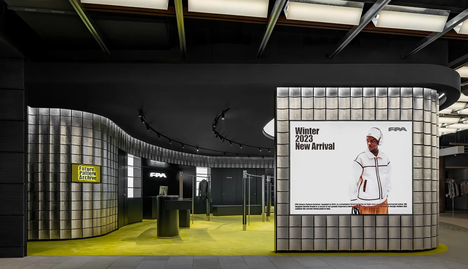 Retail storefront with metallic tile walls, black fittings, and bright yellow flooring.