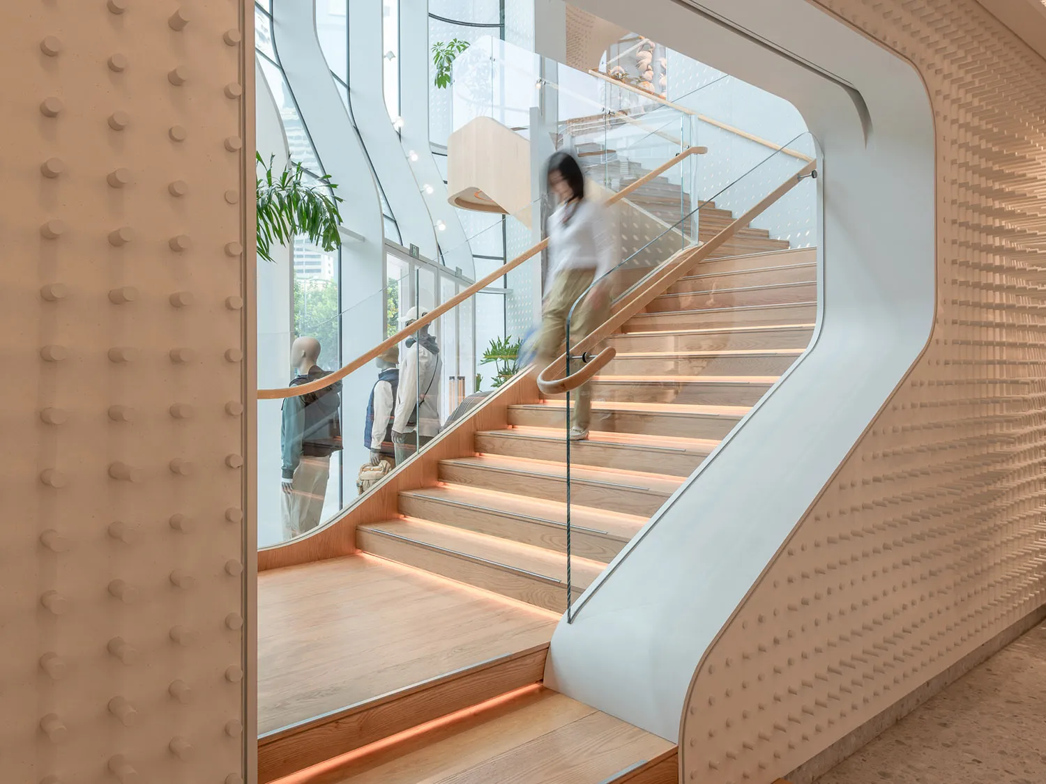 A modern retail space featuring a wooden staircase with glass railings and metal accents.