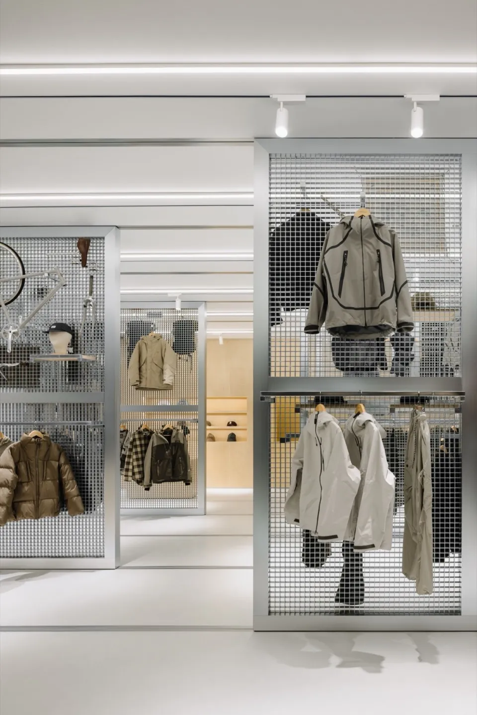 A retail storefront featuring a metal grid display wall showcasing various jackets and clothing items.