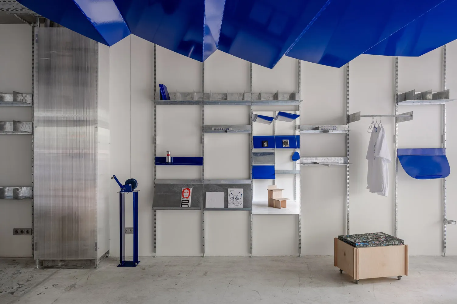 A minimalist workspace featuring metal shelving units and a blue canopy.