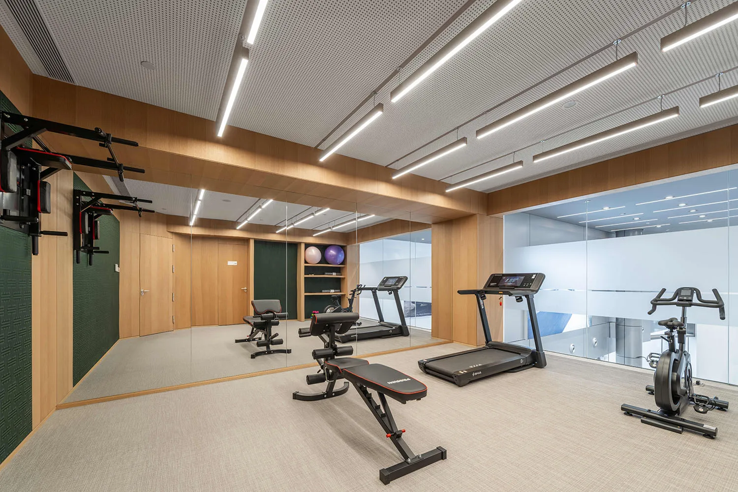 A modern gym featuring wooden flooring, exercise equipment, and workout machines.