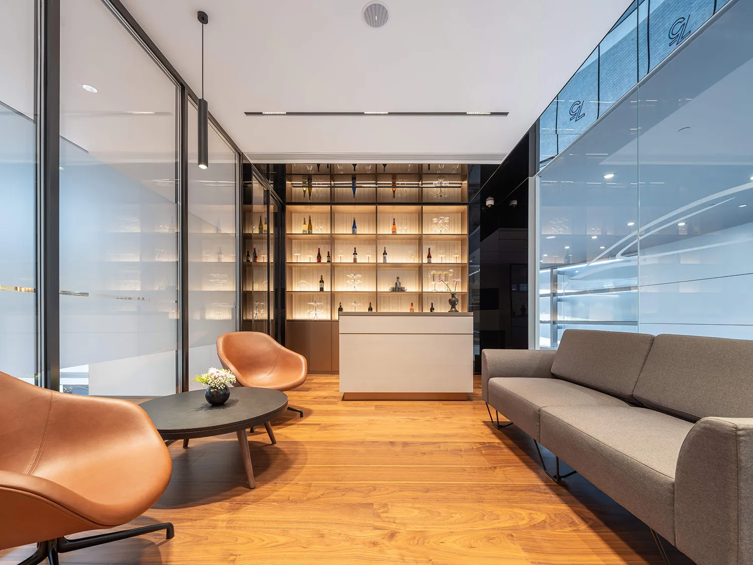 A modern office space featuring wood flooring, concrete walls, and glass partitions.
