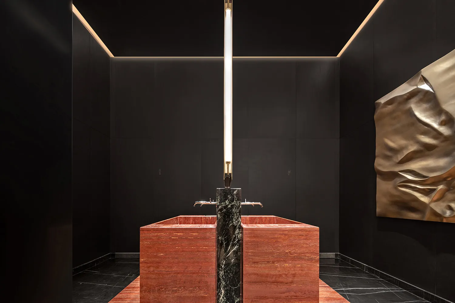Modern bathroom with a sleek, elegant marble sink and a tall, vertical light fixture in a dark, minimalist space.
