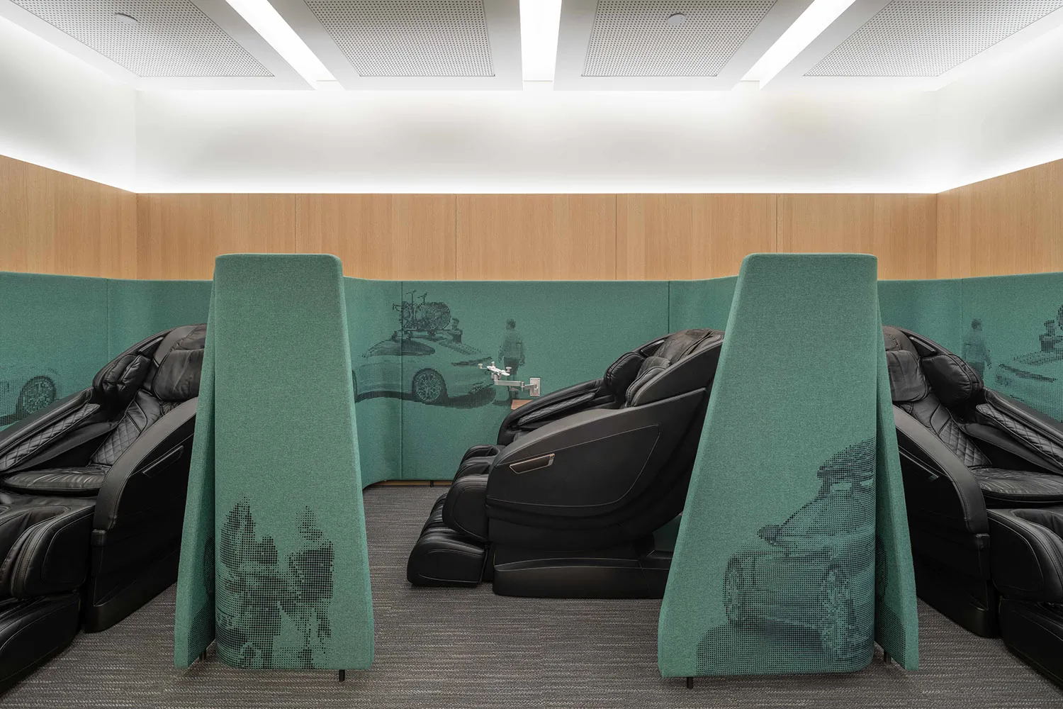 A modern interior seating area with black massage chairs and green dividers.