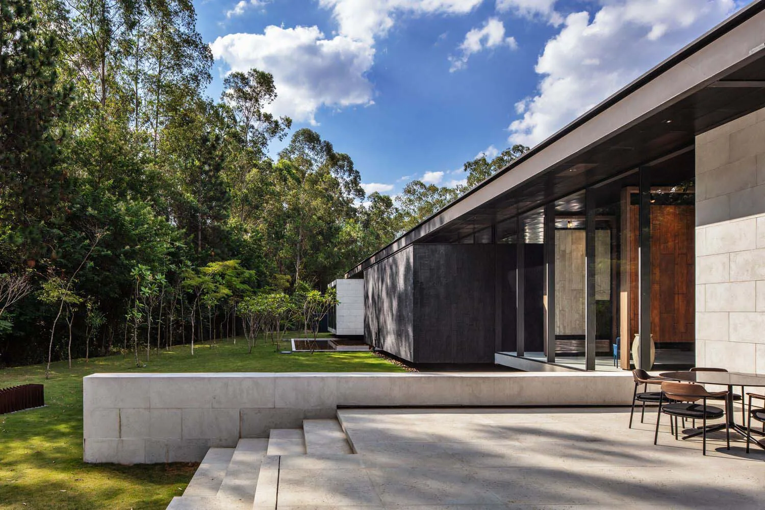 Modern private residence featuring a concrete facade and a large, open patio overlooking a grassy lawn.