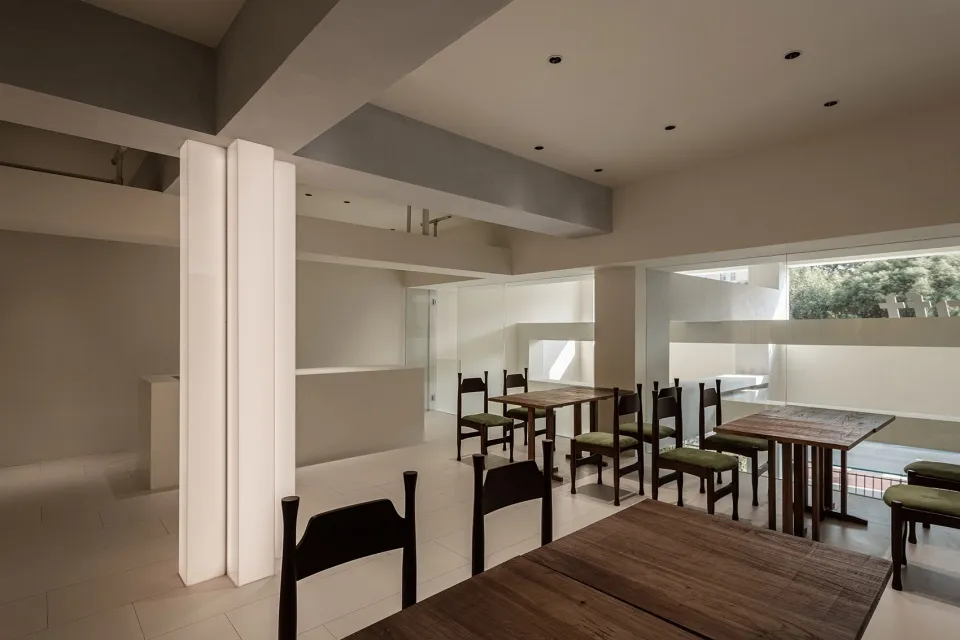 A modern minimalist restaurant interior featuring wooden tables and chairs.