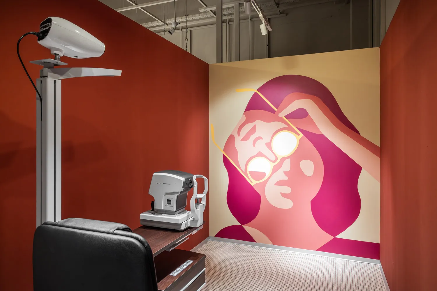 Modern examination room within a healthcare facility with industrial design elements, featuring a mural of someone adjusting