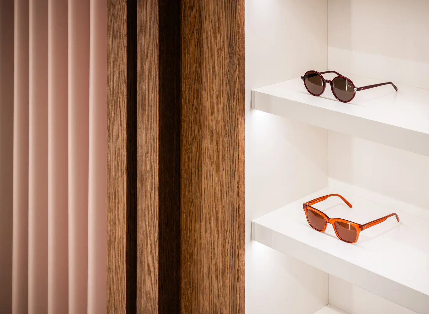 Pair of sunglasses on white wooden shelves in a retail display setting.