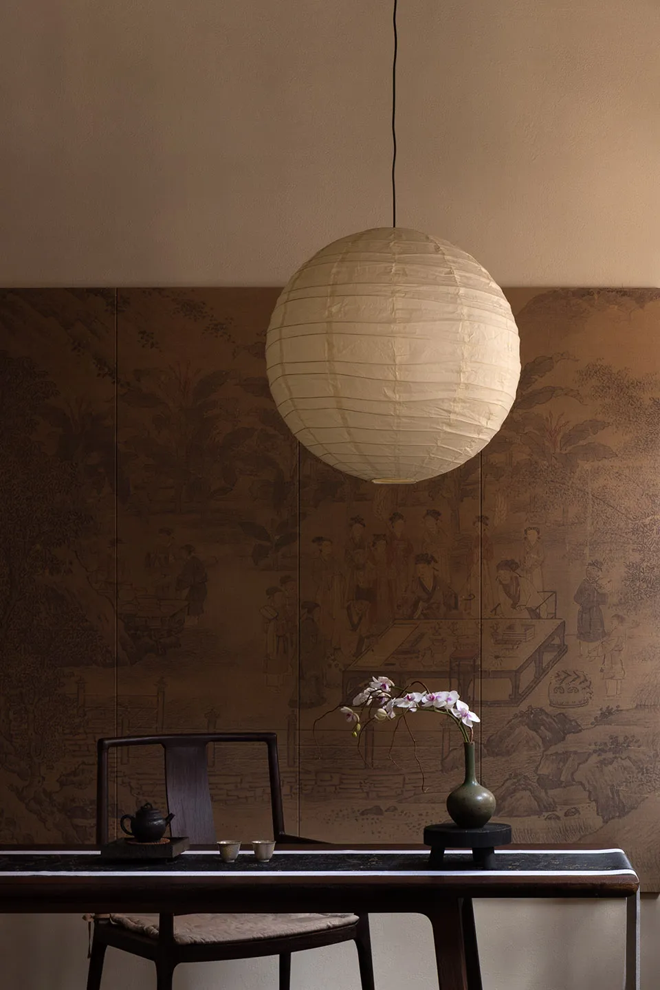 A minimalist living room featuring a white paper lantern hanging from the ceiling, creating a warm and inviting atmosphere.
