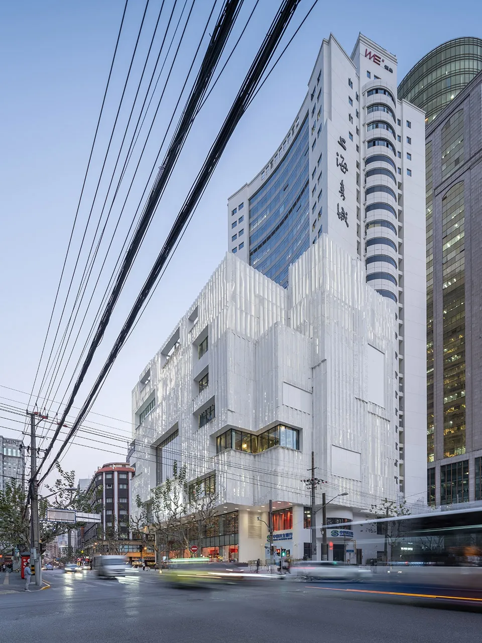 A modern commercial building featuring extensive use of glass, aluminum, and white materials.