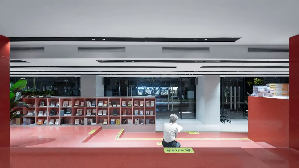 person sitting on a red concrete floor in a modern library reading room.
