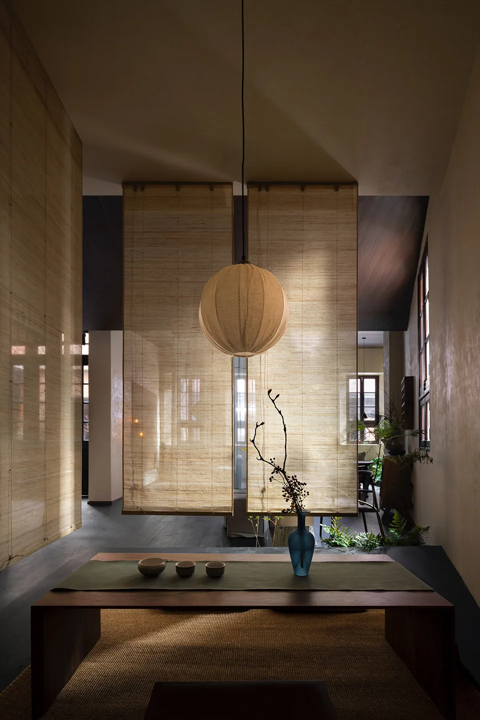 Minimalist living room featuring bamboo furniture and natural light from large windows.