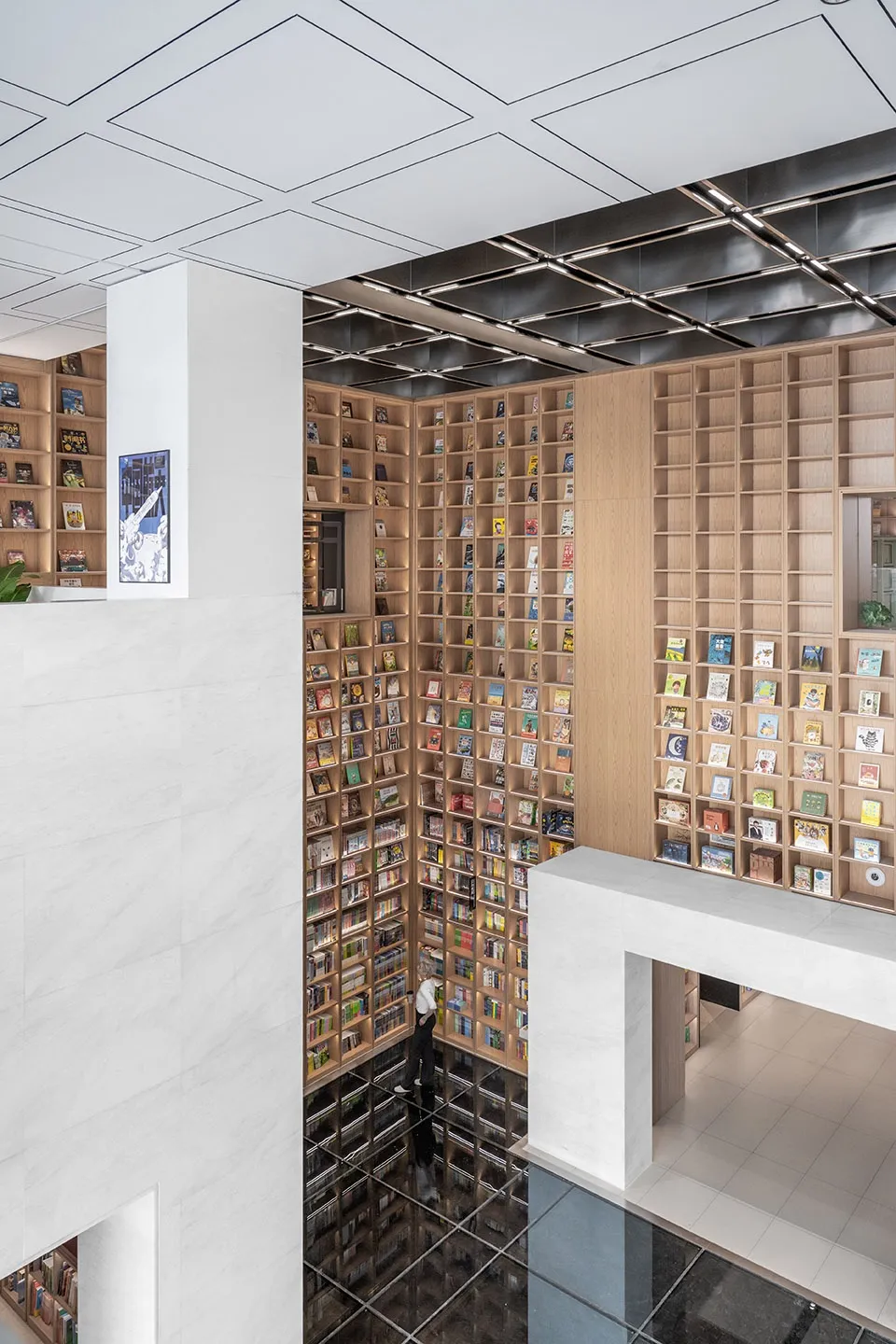 Modern library space featuring glass walls, marble columns, and wooden shelves filled with books.