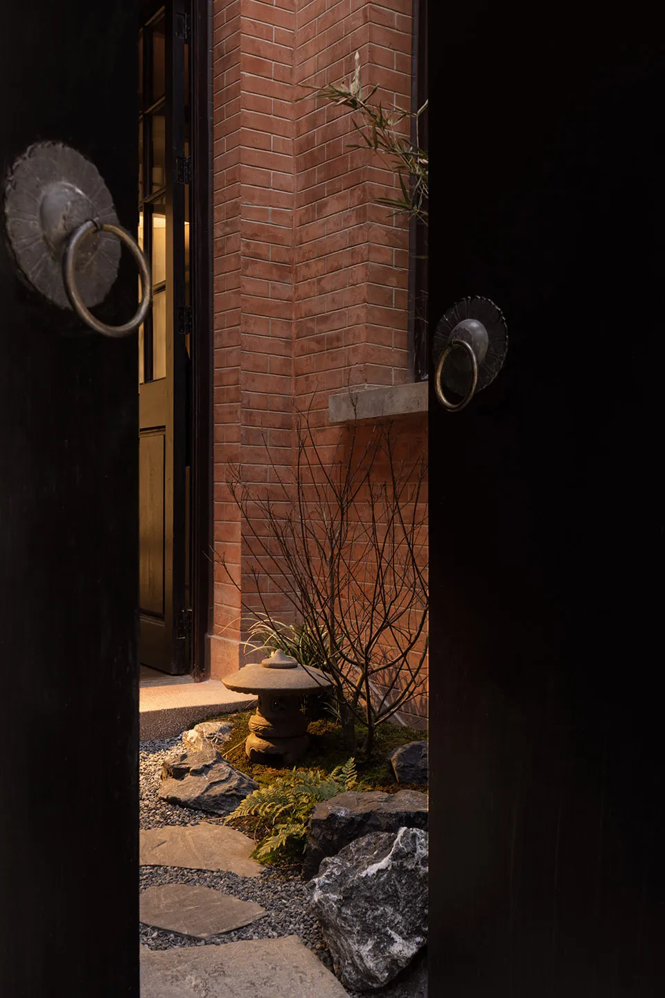 A traditional entrance with stone and brick elements, including a doorknob, pathway, and plant.