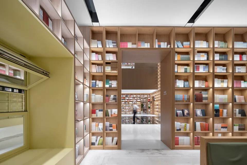 A modern library with a minimalist design and wooden shelves filled with books.