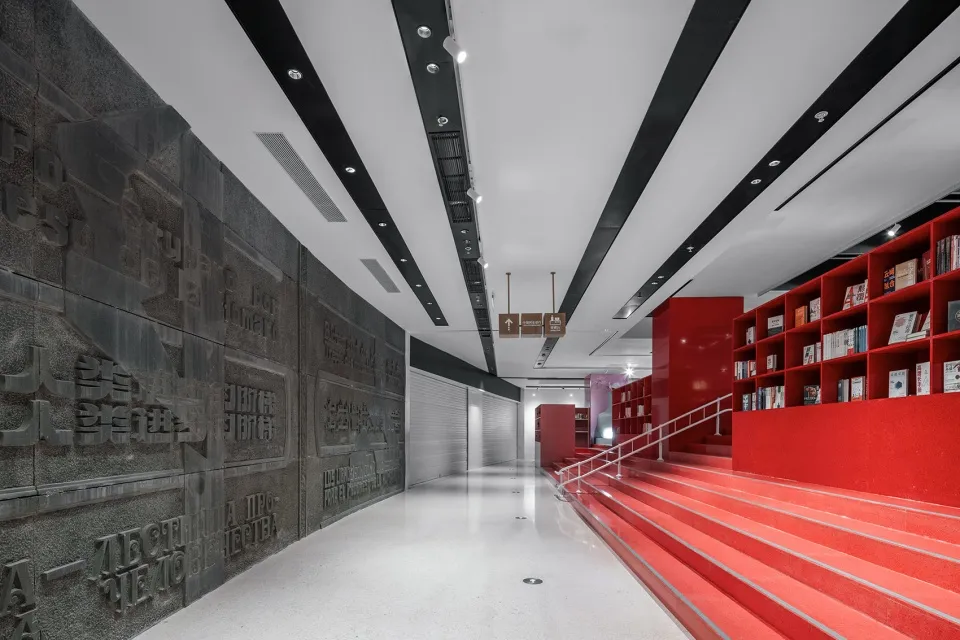 A modern library with red shelving units and concrete walls.