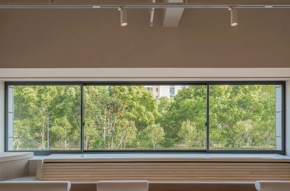 A modern window scene featuring a wooden frame with a view of lush greenery outside.