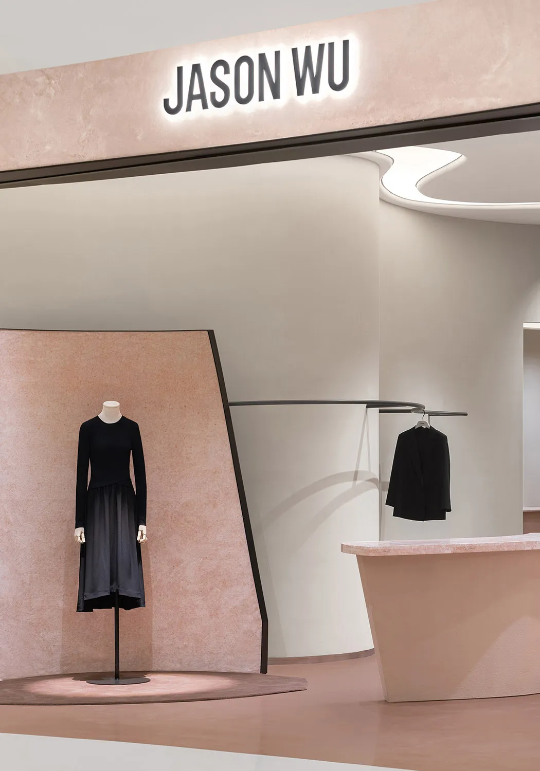 A retail storefront featuring a pink sandstone wall and a minimalist design.