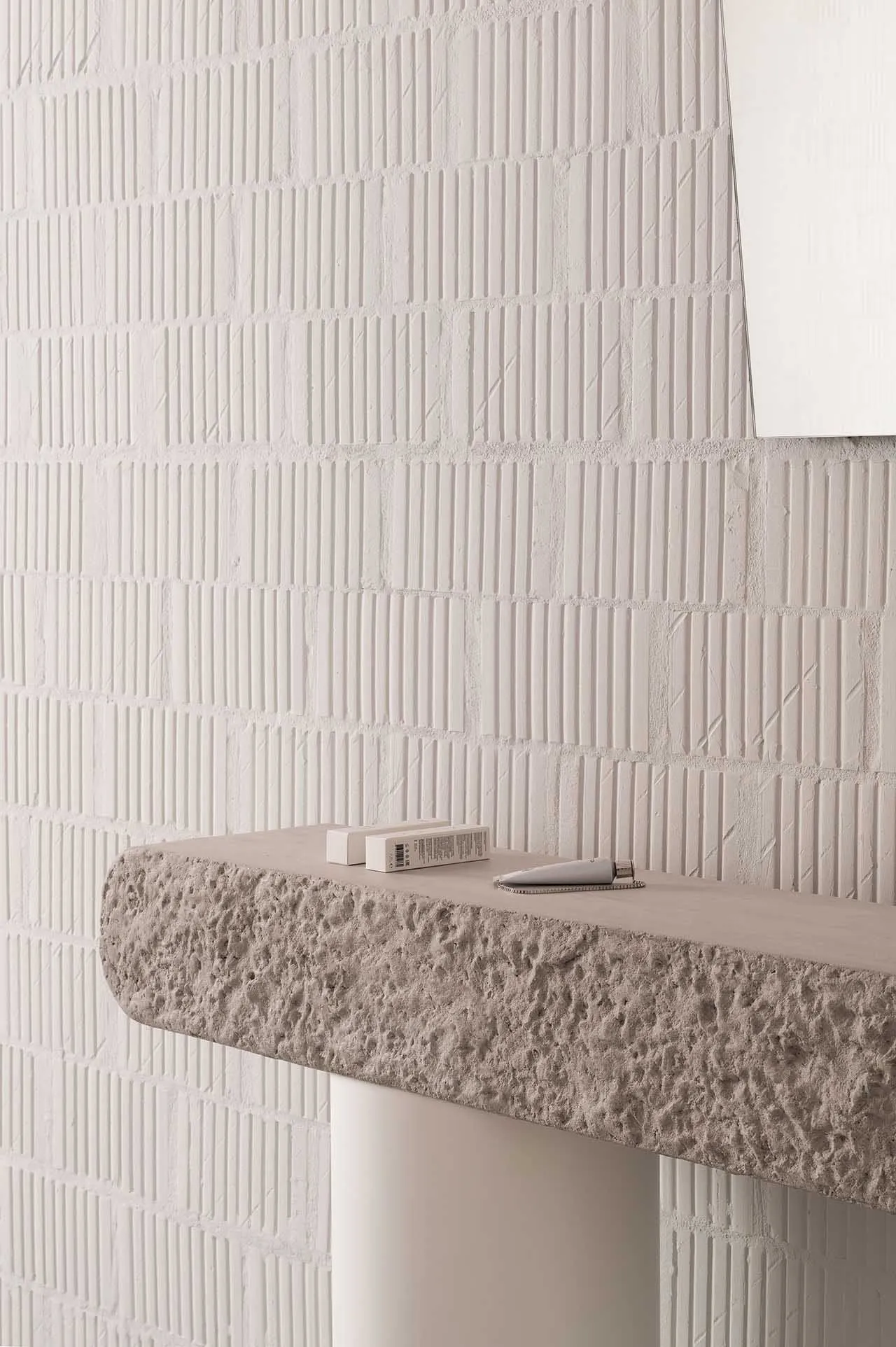 A modern minimalist interior with a textured concrete ledge against a white textured wall.